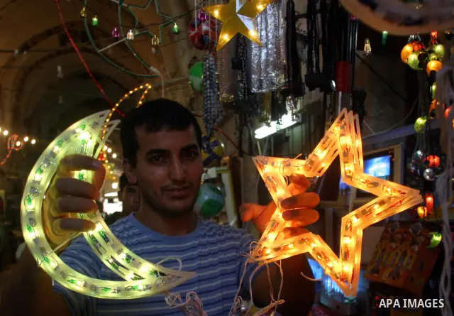 A Palestinian shopkeeper hangs up decorations before the Muslim holy month of Ramadan at a popular market in the old city of Jerusalem on August 16, 2009. Muslims around the world abstain from eating, drinking, and sexua...