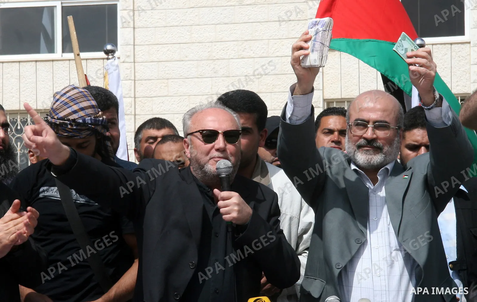 Hamas deputy prime minister Ziad al-Zaza holds up a bundle of British pounds received from British MP George Galloway (L) during a ceremony in Gaza City on March 10, 2009. Firebrand British MP George Galloway donated tho...