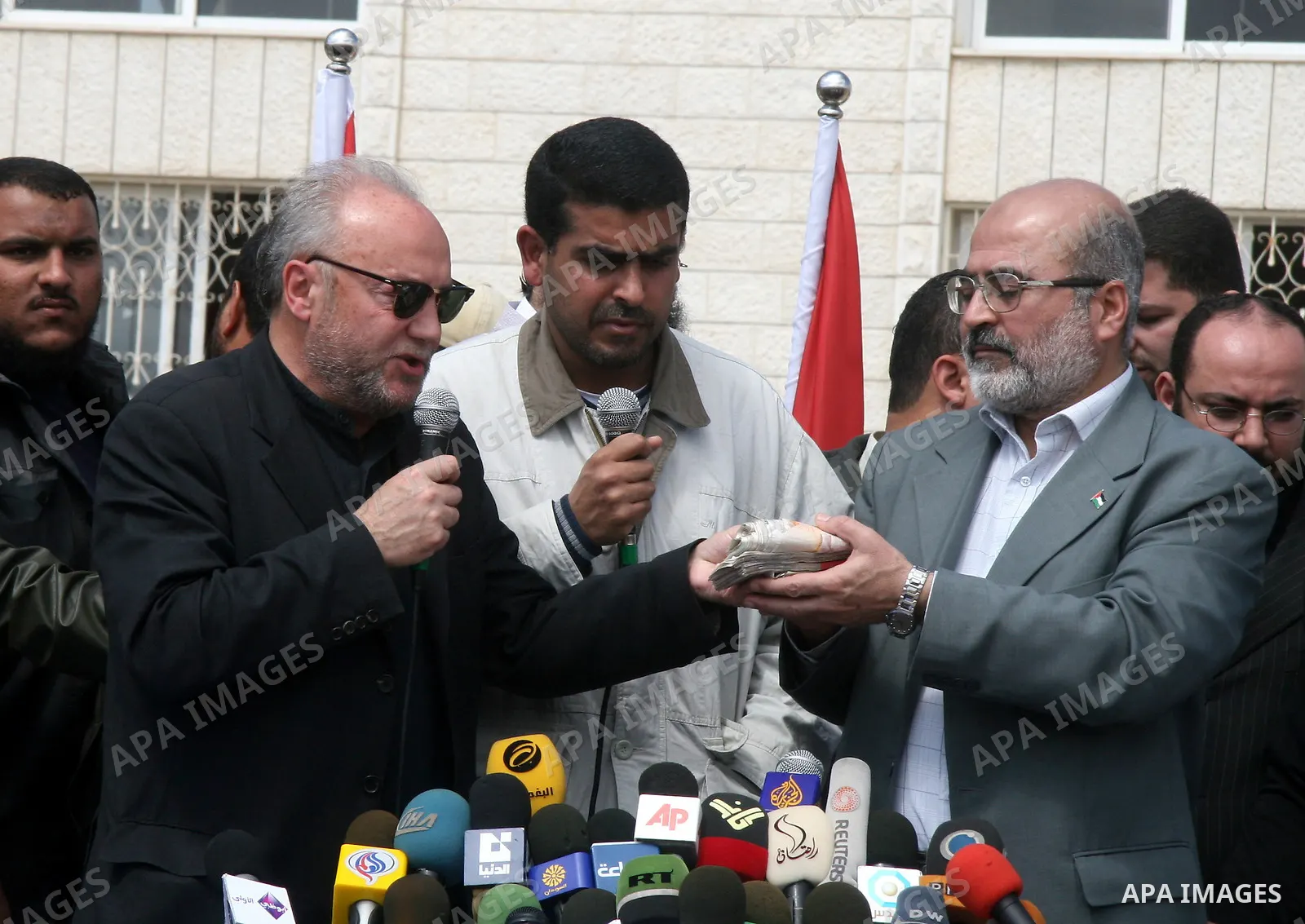 British MP George Galloway (C) hands a bundle of British pounds to Hamas deputy prime minister Ziad al-Zaza during a ceremony in Gaza City on March 10, 2009. Firebrand British MP George Galloway donated thousands of Brit...