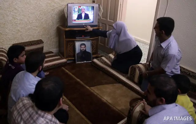 Relatives of Palestinian prisoner Rawhy Mushtaha, held in an Israeli jail, sit in thier house in Gaza City, as they watch a television broadcast of Hamas leader Khaled Meshaal speaking in Damascus, October 11, 2011. Isra...
