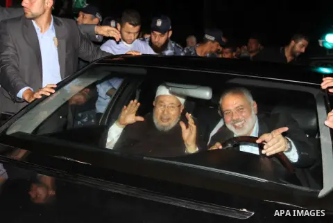 Cleric and chairman of the International Union of Muslim Scholars Sheikh Yusuf al-Qaradawi waves to the crowd as he rides in a car beside Palestinian Prime Minister in Gaza Strip Ismail Haniyeh upon al-Qaradawi's arrival...