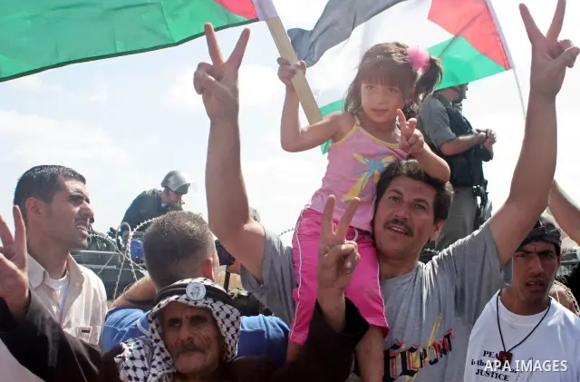 A Palestinians flashes the Victory sign next to an Israeli soldiers to celebrate the Israeli Supreme Court's resolution to redraw the route of Israel's separation barrier during a rally in the West Bank village of Bilin...