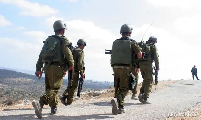 Israeli soldiers watch the Palestinians celebration near Israel's controversial separation wall near the West Bank village of Bilin. Palestinians celebrated a ruling by Israel's Supreme Court that a part of the controver...