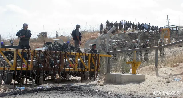 Israeli soldiers watch the Palestinians celebration near Israel's controversial separation wall near the West Bank village of Bilin. Palestinians celebrated a ruling by Israel's Supreme Court that a part of the controver...