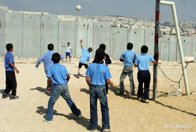palestinian students play football in playground after they come back from their school next the separation wall near the west bank village of anabta.
