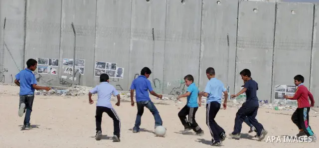 palestinian students play football in playground after they come back from their school next the separation wall near the west bank village of anabta.