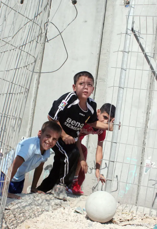 palestinian students play football in playground after they come back from their school next the separation wall near the west bank village of anabta.