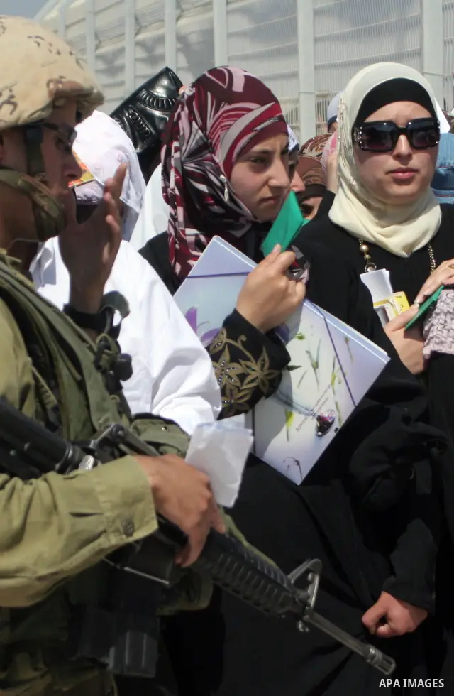 Israeli soldiers stand by Palestinians crossing the Hawara checkpoint near the West Bank city of Nablus. Prime Minister Ehud Olmert on Sunday hinted there would be no major breakthroughs in peacemaking ahead of a U.S. sp...