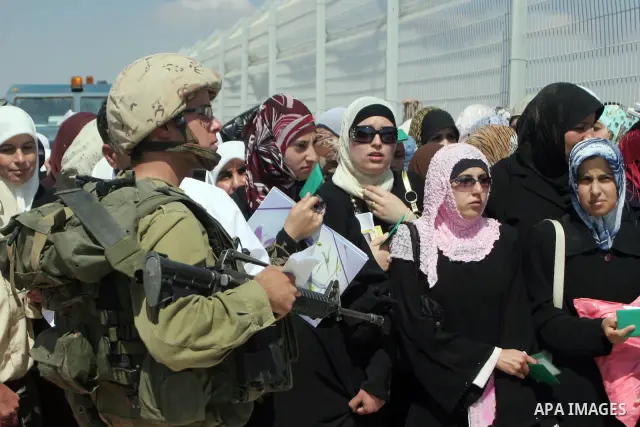 Israeli soldiers stand by Palestinians crossing the Hawara checkpoint near the West Bank city of Nablus. Prime Minister Ehud Olmert on Sunday hinted there would be no major breakthroughs in peacemaking ahead of a U.S. sp...