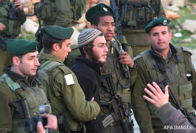 Israeli border policemen detain an Israeli settler after a group from the Kiryat Arbaa settlement attacked Palestinian cars and homes and blocked a main road in the West Bank city of Hebron on March 13, 2011. Israeli pol...