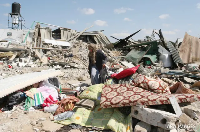 Palestinians inspect the rubble of a house, which was demolished by the Israeli army during a military operation in El-Bureig, Gaza strip