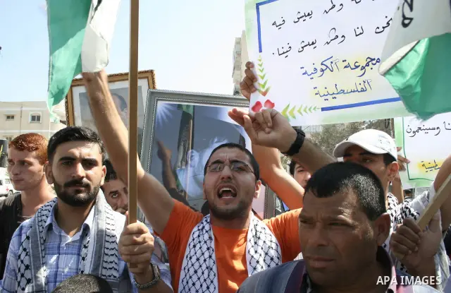 Palestinian men hold pictures of prisoners held in Israeli jails during a protest calling for their release, outside the International Red Cross building in Gaza City.