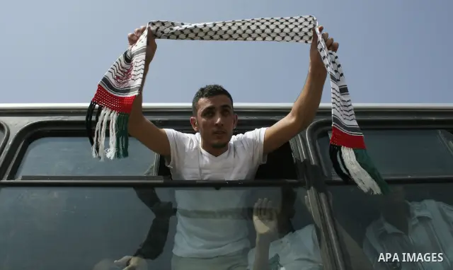 Palestinians released from Israeli jail waves banners from a bus after crossing into the Gaza Strip, following their release at the Erez crossing by Israeli border police. Israel sent 29 Palestinian prisoners back to the...