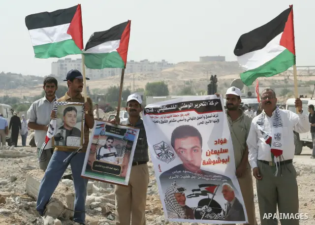 Palestinian men hold up the national flags as they welcome back prisoners released from Israeli prisons at the Erez checkpoint in the northern Gaza Strip. Israel sent 29 Palestinian prisoners back to the Gaza Strip on Tu...