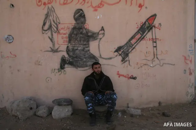 Members of Hamas security forces sit in front of anti-Israel graffiti in the northern Gaza Strip February 15, 2009. Prospects for a stable truce in Gaza ran into trouble on Saturday when Israel insisted on the release of...