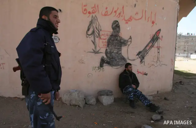 Members of Hamas security forces sit in front of anti-Israel graffiti in the northern Gaza Strip February 15, 2009. Prospects for a stable truce in Gaza ran into trouble on Saturday when Israel insisted on the release of...