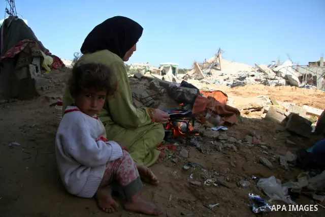 A Palestinian woman Amna al-Attar, cooks on a wood fire in front of her house, which was burnt during the Israeli operation in al-Attatra neighborhood in Beit Lahiya town in the northern Gaza Strip,15 February 2009. APAI...