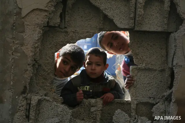 Palestinian children peep through bombed building holes during a visit by European Union (EU) Parliament President Hans-Gert Poettering to a Jabalia district that was hit during Israel's 22-day offensive on the Gaza Stri...