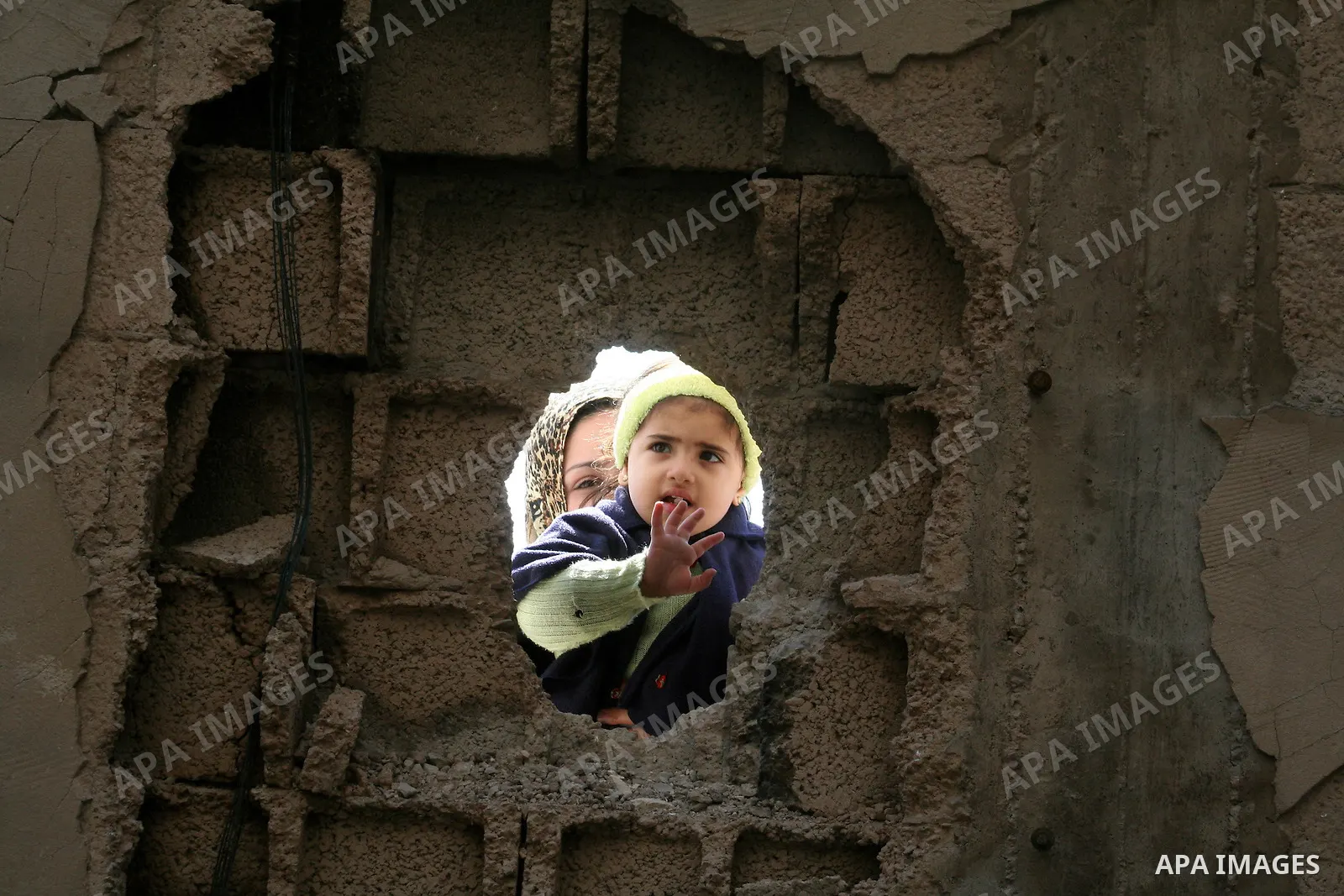 Palestinian children peep through bombed building holes during a visit by European Union (EU) Parliament President Hans-Gert Poettering to a Jabalia district that was hit during Israel's 22-day offensive on the Gaza Stri...
