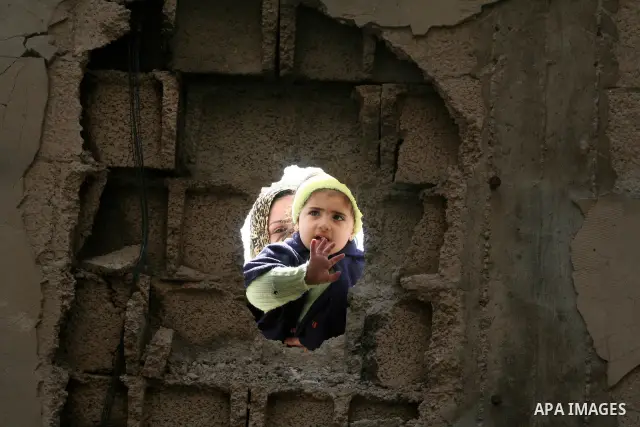 Palestinian children peep through bombed building holes during a visit by European Union (EU) Parliament President Hans-Gert Poettering to a Jabalia district that was hit during Israel's 22-day offensive on the Gaza Stri...
