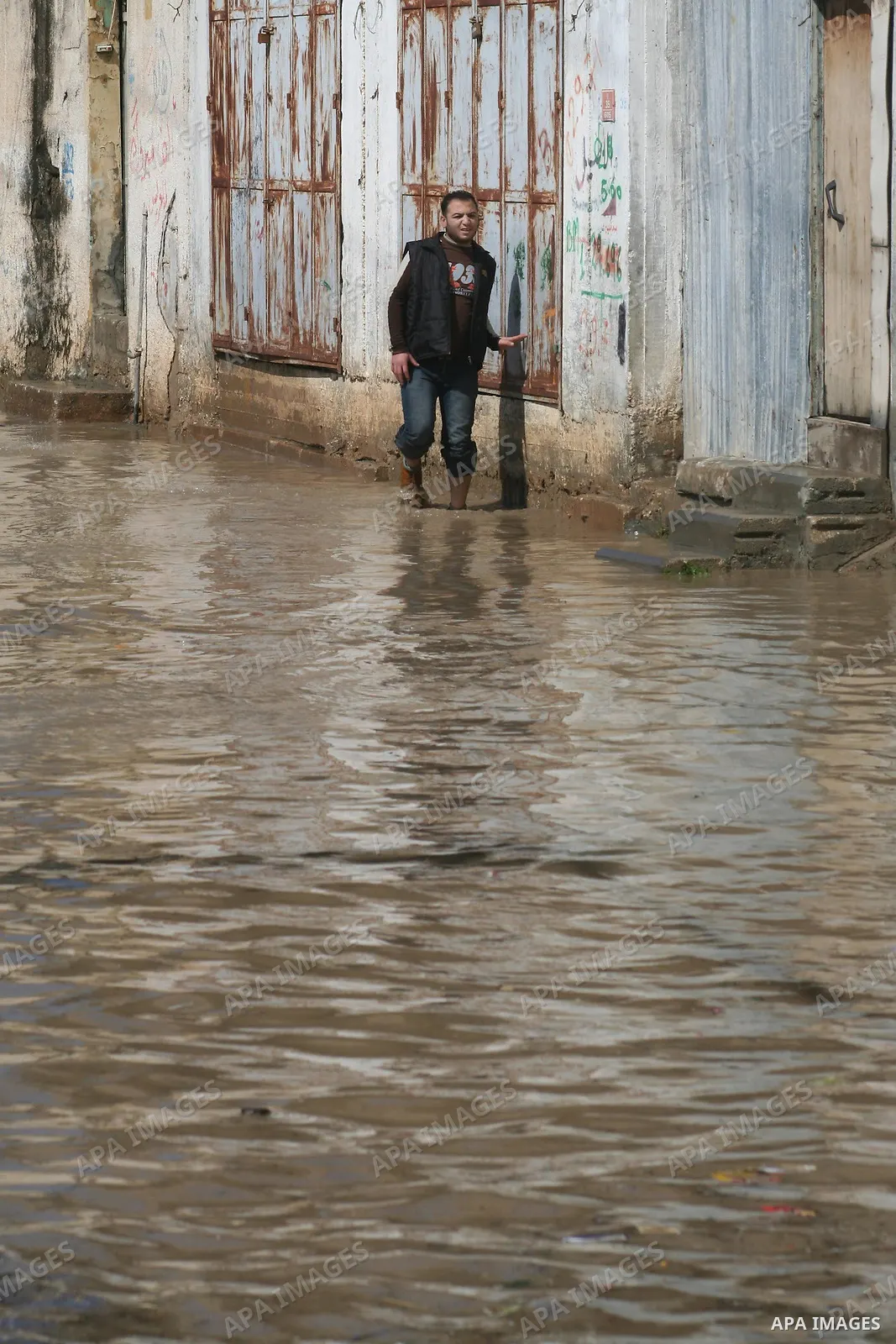 A Palestinian man tries to remove water from his front steps as the street floods during a heavy rainstorm in northern gaza strip, Sunday, March 1, 2009. APAIMAGES PHOTO / Ashraf Amra