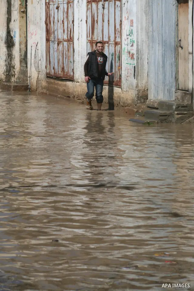 A Palestinian man tries to remove water from his front steps as the street floods during a heavy rainstorm in northern gaza strip, Sunday, March 1, 2009. APAIMAGES PHOTO / Ashraf Amra