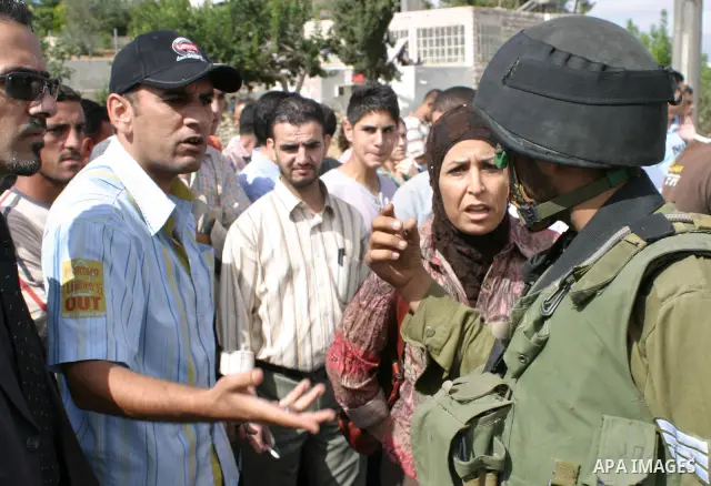 Israeli soldiers stand guard as Palestinians wait to cross a checkpoint into the West Bank city of Hebron. The Israeli army killed a top Hamas militant in Hebron on Sunday, prompting vows of revenge by the Islamist ruler...