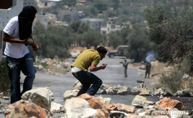 Palestinian youths hurl stones at Israeli soldiers during a demonstration against the construction of the controversial Israeli cement barrier in the West Bank village of Nilin near Ramallah.