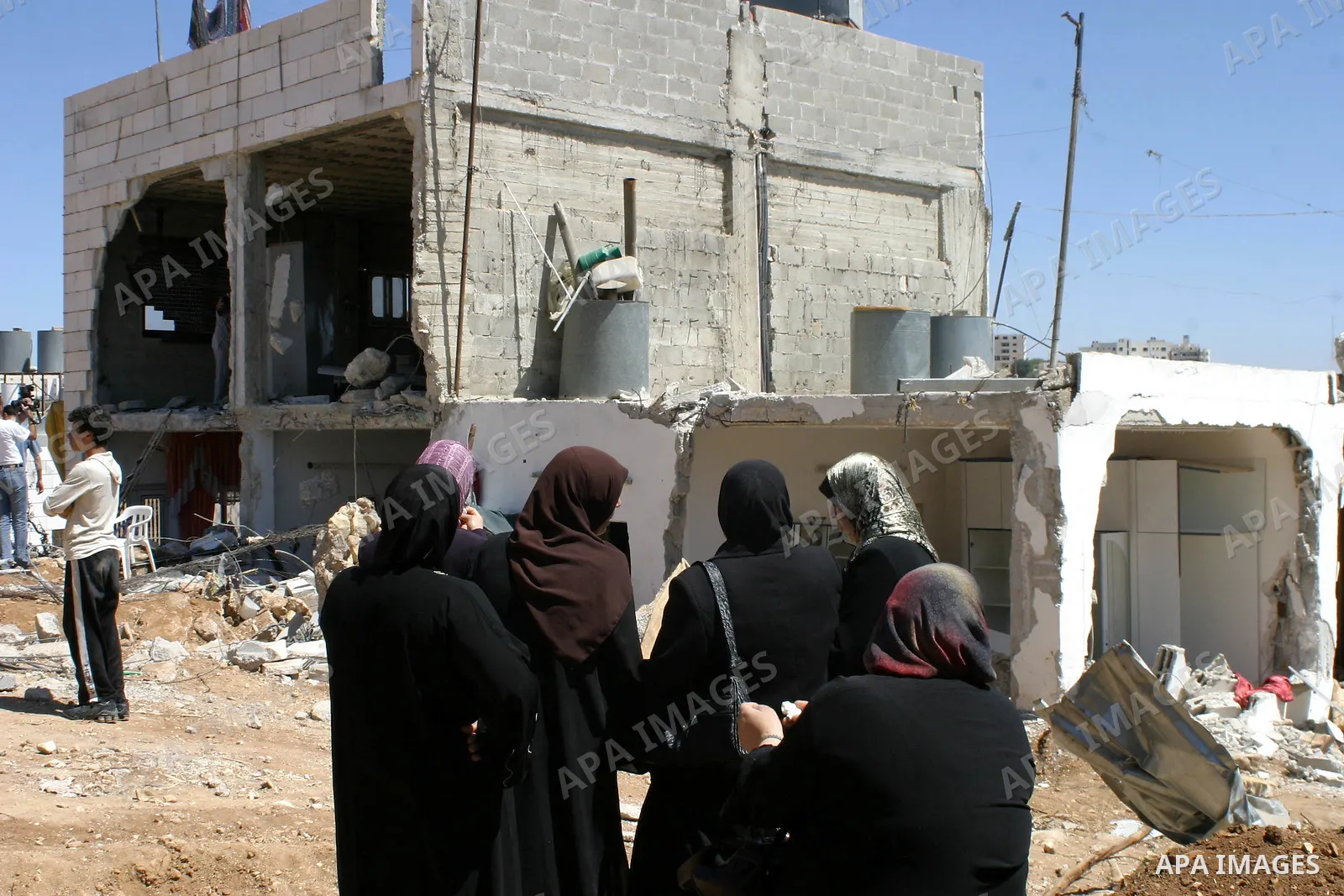 Palestinians react as they inspect their destroyed house of Jamal Karameh in the West Bank town of Hebron. According to Palestinian witnesses, Israeli forces raided two houses and arrested several men during an early mor...
