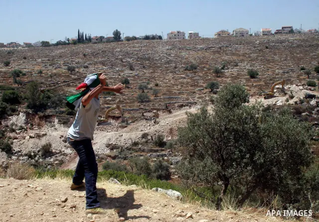 Palestinian youths throw stones at Israeli border police officers during a protest against the construction of Israel's controversial barrier in the West Bank village of Nilleen, near Ramallah.