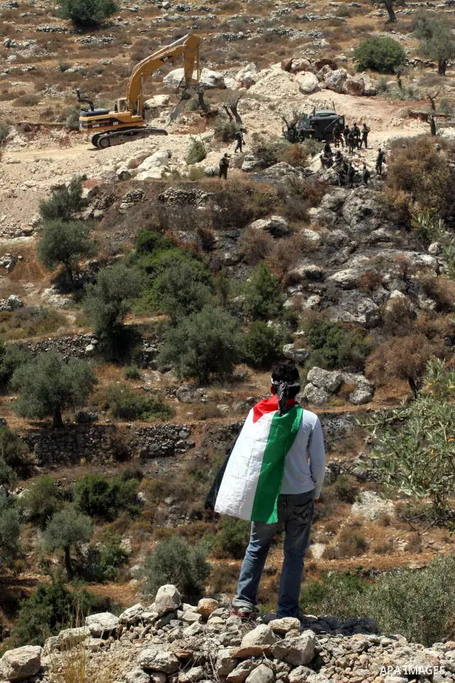 Palestinian youths throw stones at Israeli border police officers during a protest against the construction of Israel's controversial barrier in the West Bank village of Nilleen, near Ramallah.