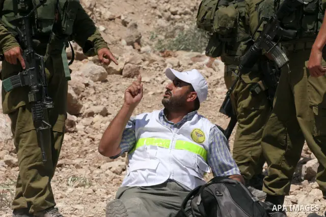 Israeli border police officers threatens Palestinians demonstrators during a violent protest against the construction of Israel's controversial security fence in the West Bank village of Nilin, west of Ramallah.