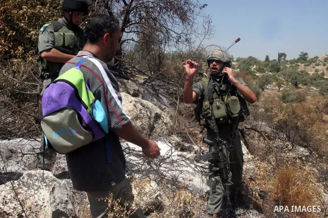 Israeli border police officers threatens Palestinians demonstrators during a violent protest against the construction of Israel's controversial security fence in the West Bank village of Nilin, west of Ramallah.