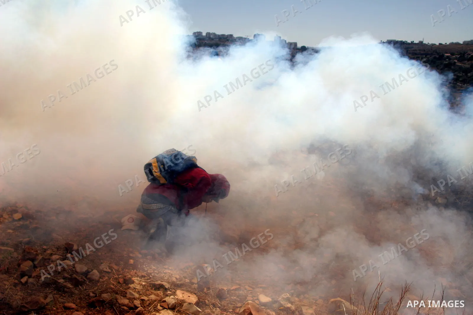 Palestinian demonstrators run from a cloud of teargas fired by Israeli troops during a protest against the construction of Israel's controversial separation barrier in the West Bank village of Nilin, west of Ramallah.