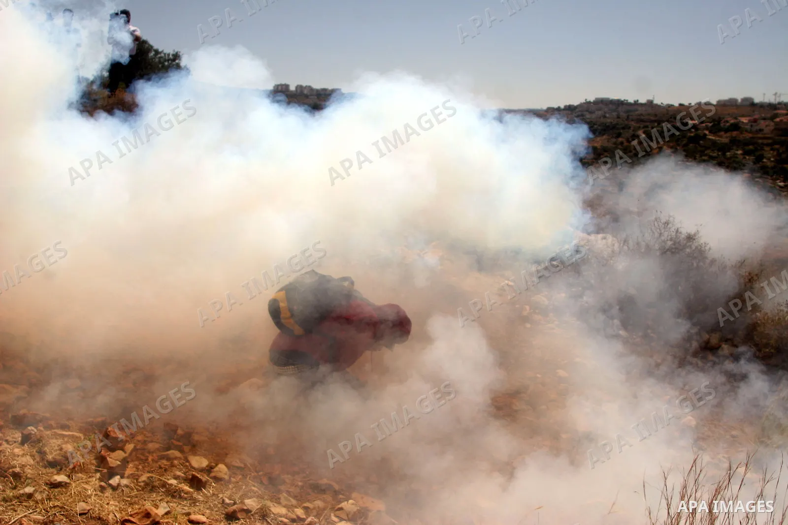 Palestinian demonstrators run from a cloud of teargas fired by Israeli troops during a protest against the construction of Israel's controversial separation barrier in the West Bank village of Nilin, west of Ramallah.