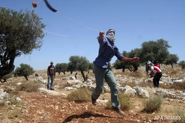 Palestinian youths throw stones at Israeli border police officers during a protest against the construction of Israel's controversial barrier in the West Bank village of Nilleen, near Ramallah.