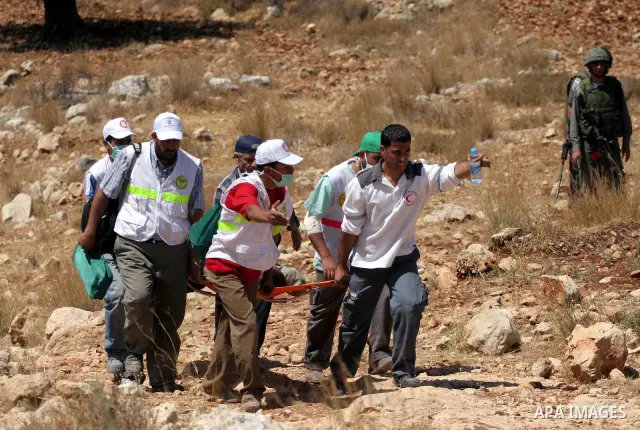Palestinian medics carry a wounded during a demonstration against the construction of the controversial Israeli barrier in the West Bank village of Nilleen near Ramallah.