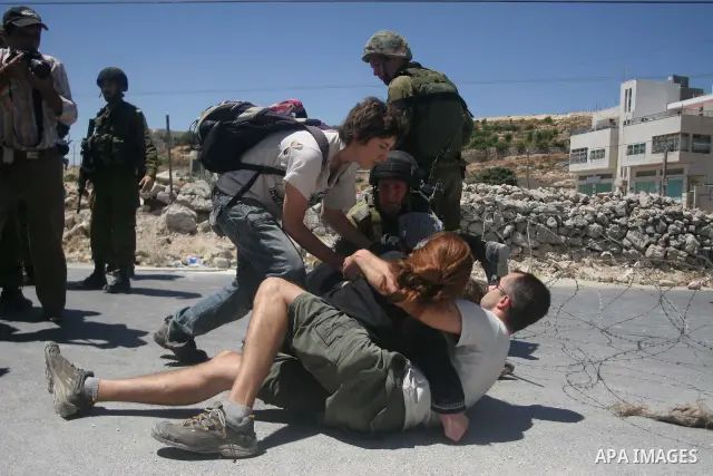 Israeli soldiers detain a foreign activists during a demonstration against the construction of the controversial Israeli separation barrier in the village of Maasarah near the West Bank town of Bethlehem. Israel says the...