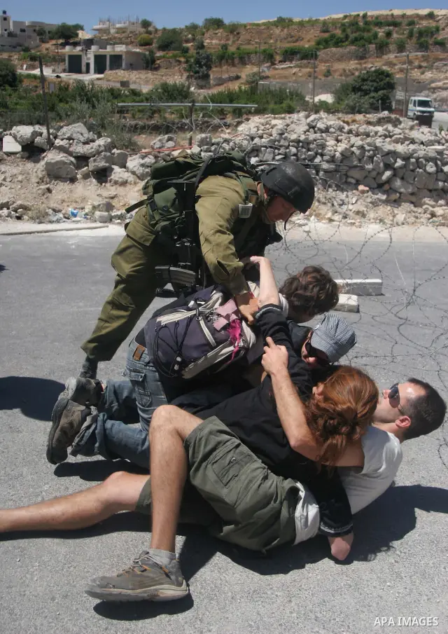 Israeli soldiers detain a foreign activists during a demonstration against the construction of the controversial Israeli separation barrier in the village of Maasarah near the West Bank town of Bethlehem. Israel says the...