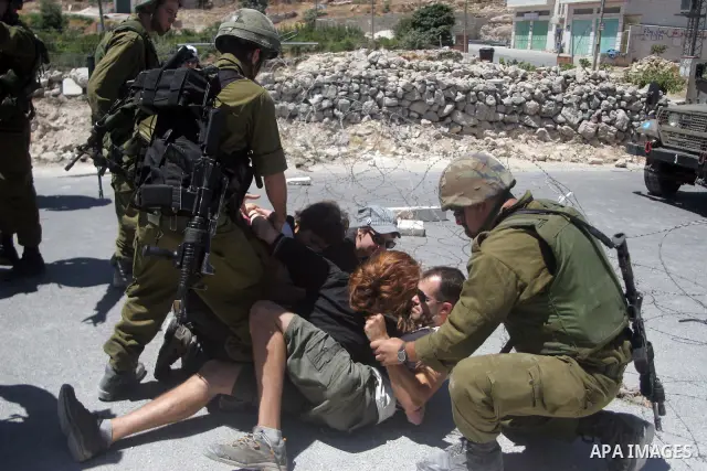 Israeli soldiers detain a foreign activists during a demonstration against the construction of the controversial Israeli separation barrier in the village of Maasarah near the West Bank town of Bethlehem. Israel says the...