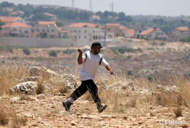 Palestinians hurl stones at Israeli border police officers during a demonstration against the construction of Israel's disputed barrier in the West Bank village of Nilleen near Ramallah.
