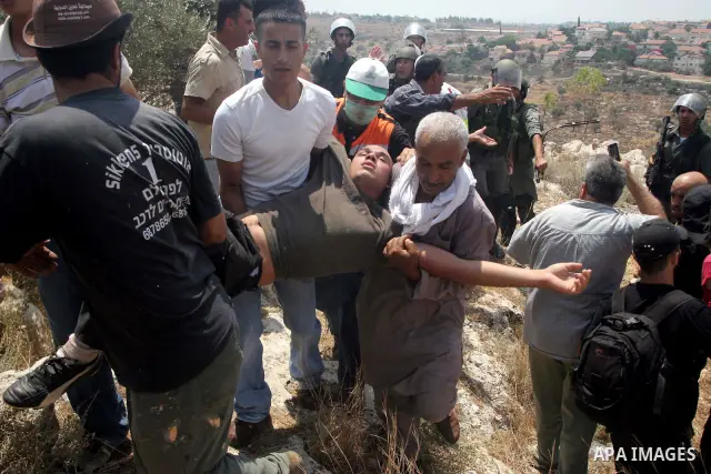 Palestinians carry a wounded during a demonstration against the construction of the controversial Israeli cement barrier in the West Bank village of Nilin near Ramallah. Sixteen Palestinians and one Israeli were lightly...