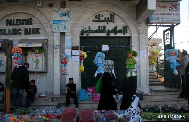 Palestinians stand in front of closed doors of Palestine in Gaza City. Banks in the Gaza Strip closed their branches today due to lack of liquidity and Israel's refusal to authorise cash transfers to the besieged territo...