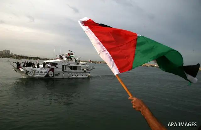 Palestinians hold the Palestinian and Qatari flags as a boat carrying members of the 'Free Gaza' group arrives from Cyprus at the port in Gaza City. Fifteen International activists, including two from a Qatari charity, a...