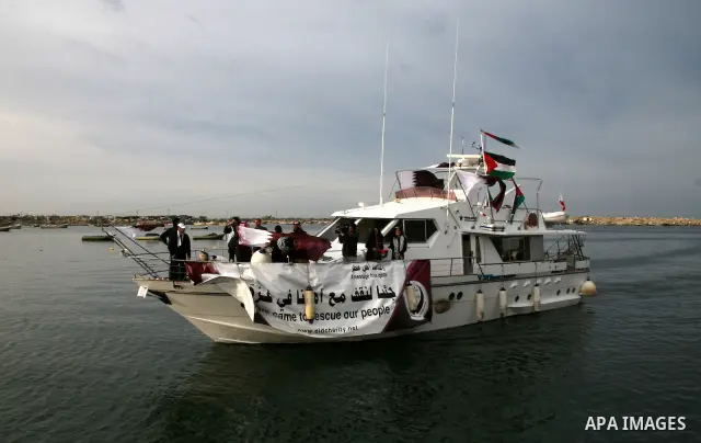 Palestinians hold the Palestinian and Qatari flags as a boat carrying members of the 'Free Gaza' group arrives from Cyprus at the port in Gaza City. Fifteen International activists, including two from a Qatari charity, a...