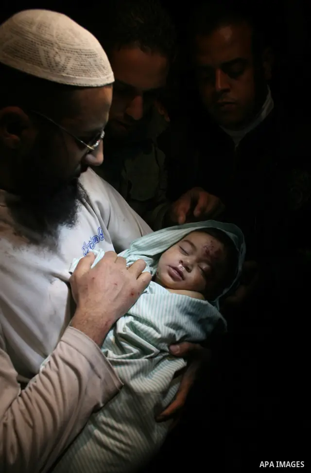 The father of Six-month-old Mohammed Bourai looks at his baby at the morgue at al-Shifa hospital in Gaza city. A baby boy was killed Wednesday when three missiles fired by an Israeli helicopter struck the interior minist...