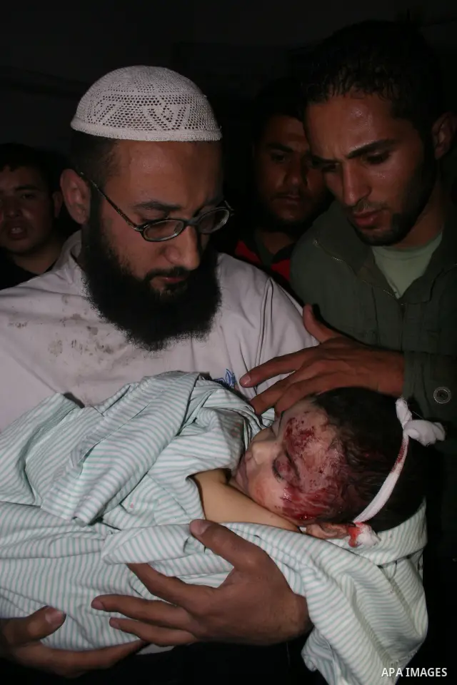 The father of Six-month-old Mohammed Bourai looks at his baby at the morgue at al-Shifa hospital in Gaza city. A baby boy was killed Wednesday when three missiles fired by an Israeli helicopter struck the interior minist...