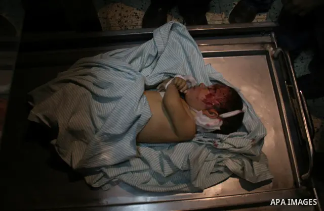The father of Six-month-old Mohammed Bourai looks at his baby at the morgue at al-Shifa hospital in Gaza city. A baby boy was killed Wednesday when three missiles fired by an Israeli helicopter struck the interior minist...