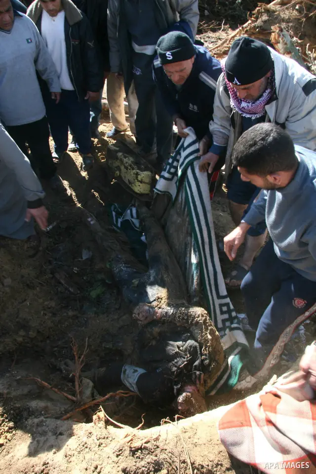 A body of a Palestinian man from the Samoni family, who was killed on Jan. 5 during an Israeli army operation in Gaza, is removed from the rubble of the family house in Gaza City, Sunday, Jan. 18, 2009. Israeli troops in...