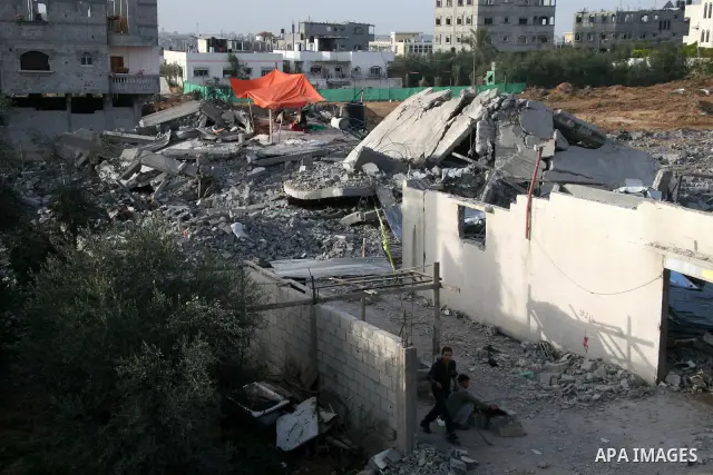 A Palestinian family sit next to their destroyed home in the area of east Jebaliya, in the northern Gaza Strip, Wednesday Jan. 28, 2009. The house was destroyed in the last Israeli military offensive. U.S. President Bara...